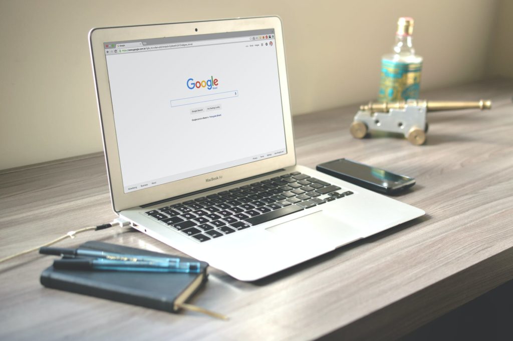A laptop displaying the Google homepage and a notebook on a desk
