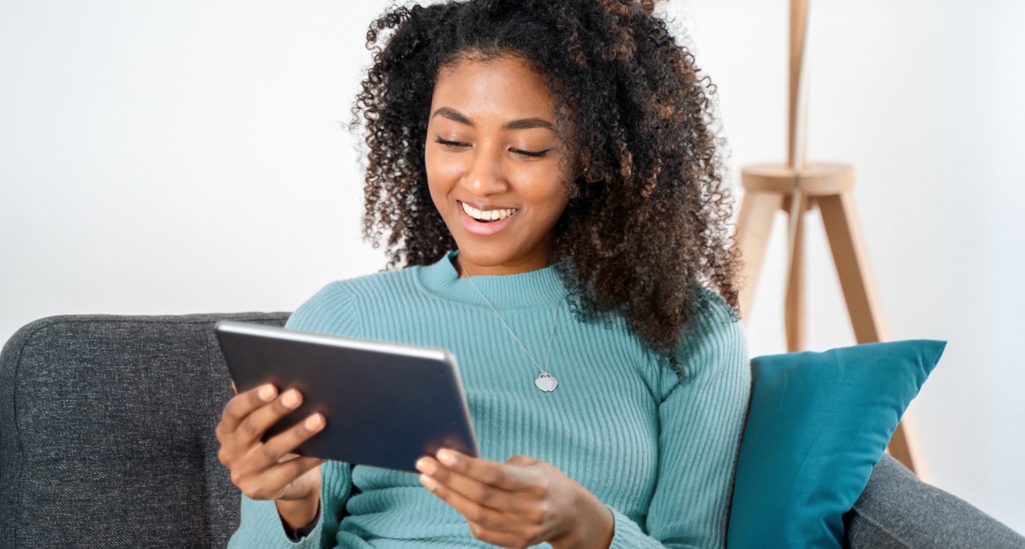 Happy black young woman using digital tablet at home